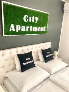 a white couch with a sign on the wall at City Apartment in Štúrovo