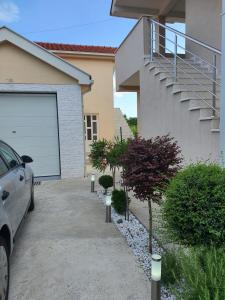 a car parked in front of a house with a garage at Apartman Tološi in Podgorica