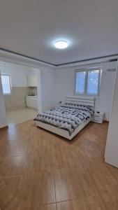ein Schlafzimmer mit einem Bett in einem Zimmer mit Holzboden in der Unterkunft Apartman Tološi in Podgorica