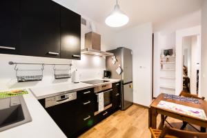 a kitchen with black and white cabinets and a table at Malborska Lovely Apartment in Warsaw