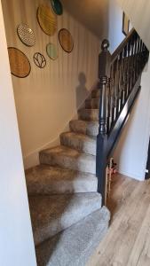 a staircase with brown carpeted stairs with wooden floors at The Farrier's by Spires Accommodation A convenient place to stay for exploring Cannock Chase in Hednesford