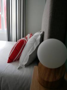 łóżko z czerwonymi i białymi poduszkami obok okna w obiekcie Auberge Trabenia w mieście Ascain