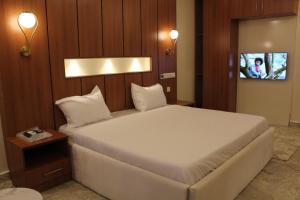 1 dormitorio con 1 cama blanca y TV en Fahrenheit Apartments, en Abuja