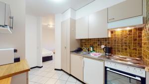 谢尔Spacious studio in a nice area in Sierre的带白色橱柜和水槽的厨房