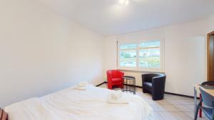 谢尔Spacious studio in a nice area in Sierre的客房设有床、两把椅子和窗户。
