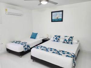 two beds in a room with white walls at Apartamento frente a la playa 5B - By Bedviajes in Santa Marta