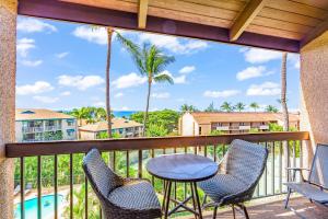 een balkon met een tafel en stoelen en een zwembad bij Maui Vista Condo 2410 in Kihei