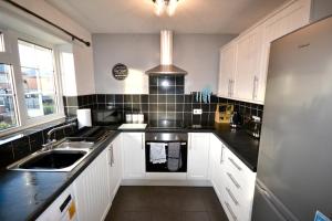 uma cozinha com armários brancos e bancadas pretas em Redmire - 2 bed 1st floor flat overlooking green em Darlington