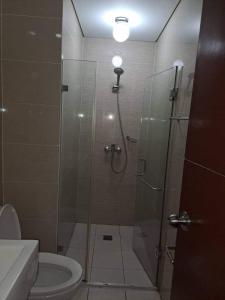 een badkamer met een glazen douche en een toilet bij Rqui CondoTel Near Airport in Manilla