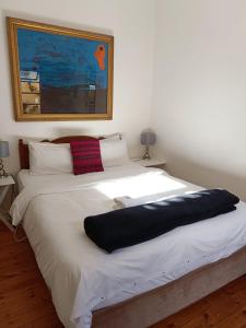 a large white bed with a black blanket on it at John Bauer Pottery Studio in Cape Town