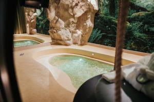 a jacuzzi tub in a room with a rock at Emotional Grand Motel in Fontaneto dʼAgogna