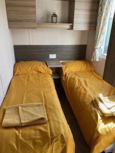 two beds in a small room with yellow sheets at Swift Retreat Caravan - Morecambe in Morecambe