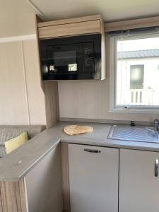 a kitchen with a counter top with a microwave at Swift Retreat Caravan - Morecambe in Morecambe