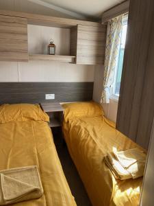 a bedroom with two beds and a desk and a window at Swift Retreat Caravan - Morecambe in Morecambe