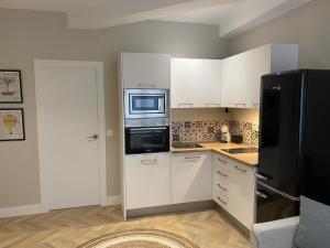 uma cozinha com armários brancos e um frigorífico preto em Apartamento Cielo del Norte VUT LE-933 em León