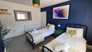 a bedroom with two beds and a table and a mirror at Worthingtons by Spires Accommodation A cosy and comfortable home from home place to stay in Burton-upon-Trent in Burton upon Trent