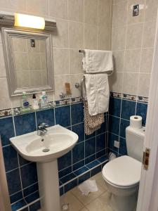 W wyłożonej niebieskimi kafelkami łazience znajduje się umywalka i toaleta. w obiekcie Lulus w mieście St Bees