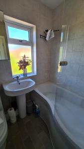 La salle de bains est pourvue d'un lavabo, d'une baignoire et d'une fenêtre. dans l'établissement Worthingtons by Spires Accommodation A cosy and comfortable home from home place to stay in Burton-upon-Trent, à Burton-on-Trent
