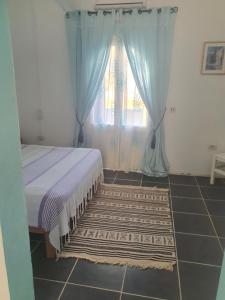 a bedroom with a bed and a window and a rug at Dar Chick Yahia Ile De Djerba in Mezrane
