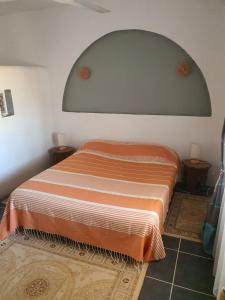 a bedroom with a bed with an orange and white blanket at Dar Chick Yahia Ile De Djerba in Mezrane