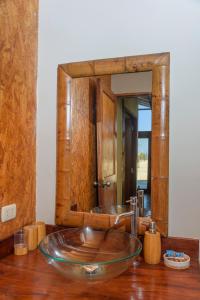 baño con lavabo de cristal frente a un espejo en Wallac Bungalows Canoas de Punta Sal, en Canoas de Punta Sal