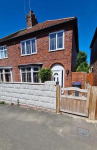a brick house with a wooden fence in front of it at Worthingtons by Spires Accommodation A cosy and comfortable home from home place to stay in Burton-upon-Trent in Burton upon Trent