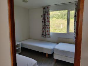 a small room with two beds and a window at Sólbrekka Guesthouse in Mjóifjörður