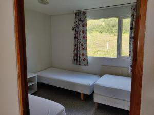 una piccola stanza con due letti e una finestra di Sólbrekka Guesthouse a Mjóifjörður