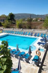 a large swimming pool with chairs and umbrellas at Hotel Tassia for families & couples in Laganas