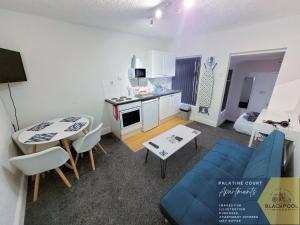 a kitchen and a living room with a table and a blue couch at Palatine Court Holiday Flats - Blackpool Resort Collection in Blackpool