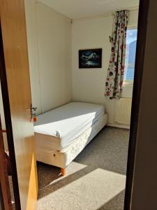 una piccola camera da letto con un letto e una finestra di Sólbrekka Guesthouse a Mjóifjörður