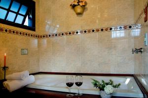 ein Badezimmer mit einer Badewanne und zwei Gläsern Wein in der Unterkunft Hotel Bühler in Visconde De Maua