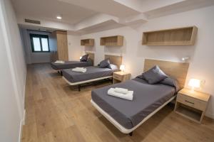 a room with two beds and two night stands at Micampus Leganés in Leganés
