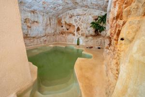 een zwembad met groen water in een kamer met een stenen muur bij Lamia with pool in Ostuni