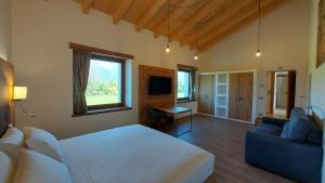 a bedroom with a white bed and a blue couch at Corte Varola B&B Zia Marisa in Belluno