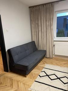 a black couch in a living room with a window at Dom w Nowym Sączu przy Miasteczku Galicyjskim in Nowy Sącz