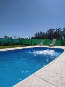 a swimming pool with two chairs and a fence at Casa quinta La Justina in Concepción del Uruguay