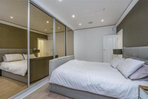 um quarto com uma grande cama branca e espelhos em Modern 4 BDR 3 BTH apt minutes from Edgware Road em Londres