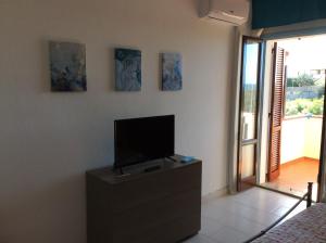 a living room with a tv on a dresser with a bed at Creúsa de ma Calasetta in Calasetta