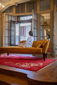 une femme assise sur un canapé dans une pièce dans l'établissement Palazzo Maria Formosa, à Venise