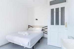 a white bedroom with a bed and a bathroom at Gran Via Experience in Madrid