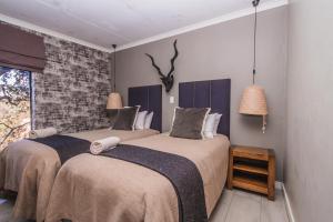 a bedroom with two beds and a brick wall at Thabela Thabeng in Parys