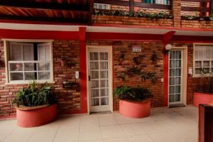 um edifício de tijolos com duas portas brancas e vasos de plantas em Pousada Brilho da Serra em Tiradentes