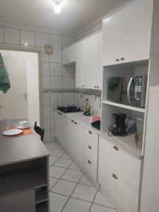 a kitchen with white cabinets and a microwave at Apartamento no coração de Porto Alegre in Porto Alegre
