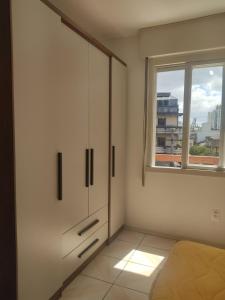 a white room with a cabinet and a window at Apartamento no coração de Porto Alegre in Porto Alegre