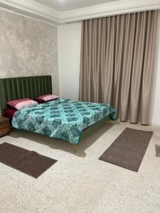 a bedroom with a bed with a green comforter at عمارة سيتي سنتر صفاقس in Sfax
