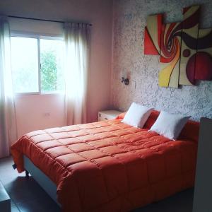 1 dormitorio con 1 cama con edredón rojo y ventana en Cabañas Paraje Noviembre en Nono