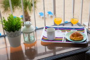 a table with a plate of food and two glasses of orange juice at SEAFRONT UNBEATABLE LOCATION a in Benidorm