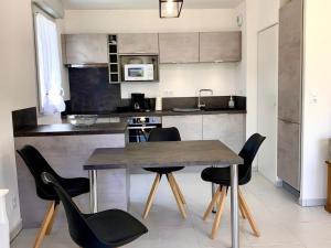 une cuisine avec une table en bois et des chaises noires dans l'établissement Appartement Mèze, 3 pièces, 4 personnes - FR-1-604-27, à Mèze