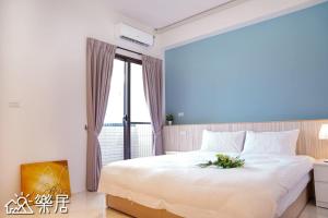 - une chambre avec un grand lit blanc et une fenêtre dans l'établissement Alley-巷弄75包棟民宿, à Yilan